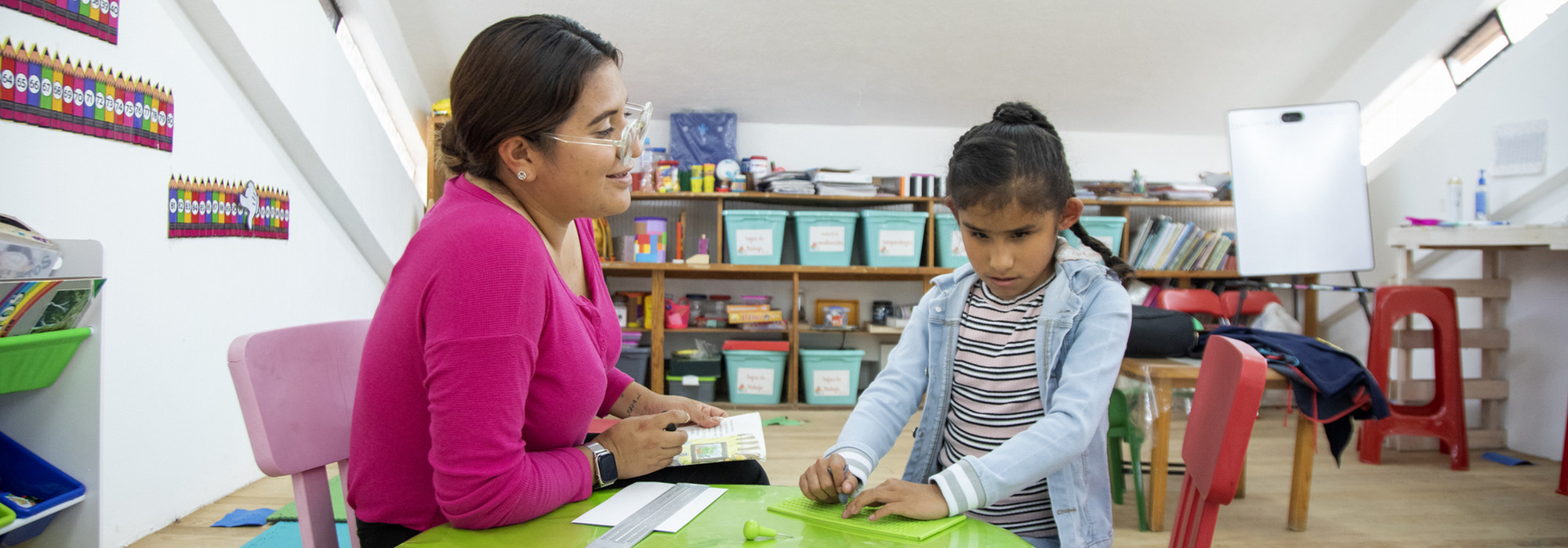 Teacher teaches blind student to write braille